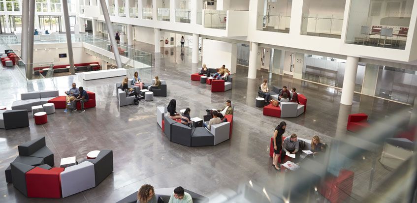 The inside of an educational facility atrium with students socialising.